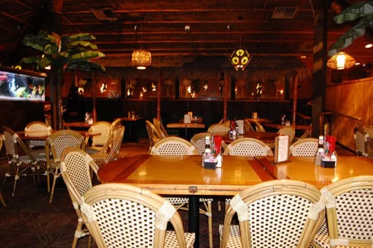 Rattan chairs around wooden tables in the main dining room, with an aquarium at left