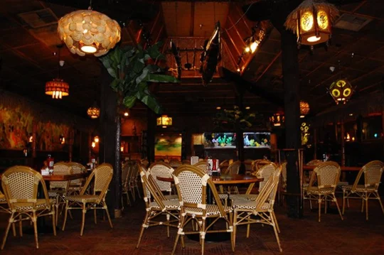 Main dining room lit by shell and pufferfish lanterns, with aquariums along the back wall